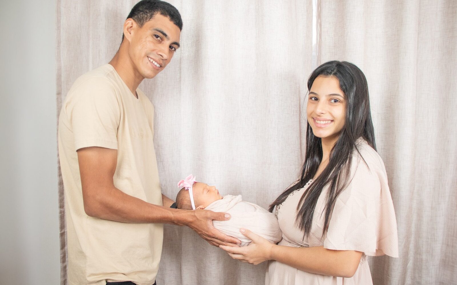 Família segurando o bebê com cuidado durante registro fotográfico